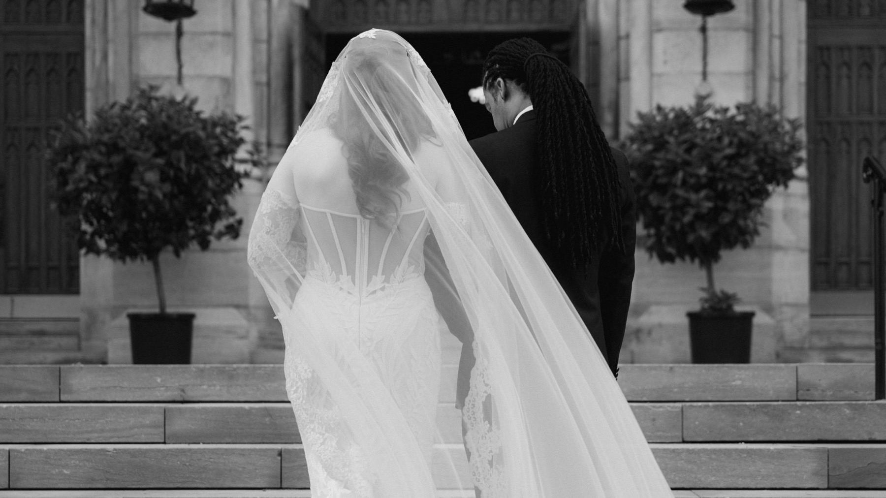 Mariée et son voile sur des marches, en noir et blanc